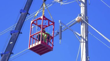  Asansördeki iki yetenekli işçi, uzun direğin elektrik bakımında güvenliği sağlıyorlar..