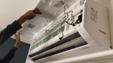 Bir teknisyen duvara monte edilmiş klimayı tamir eder ve havalandırma sistemini tamir eder.. 