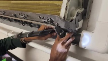 Bir teknisyen duvara monte edilmiş klimayı tamir eder ve havalandırma sistemini tamir eder.. 