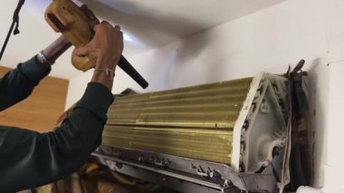 Bir teknisyen duvara monte edilmiş klimayı tamir eder ve havalandırma sistemini tamir eder.. 