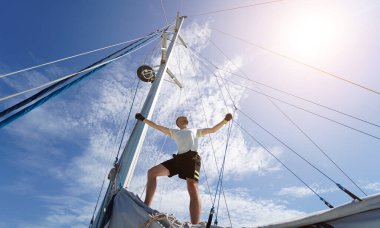 Erkek kaptan gururla bir yelkenlide durup anın tadını çıkarıyor..