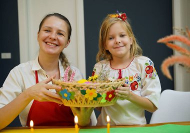 Anne ve kızı geleneksel Ukrayna kostümleriyle Paskalya için yumurta boyuyor..