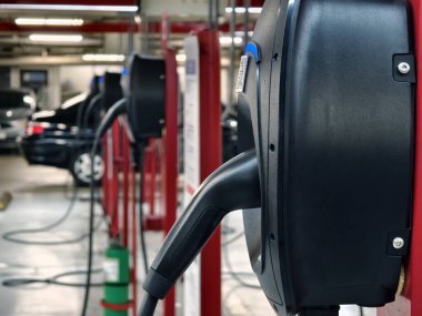 Kullanıcı kolaylığı için tüm uygun noktaları gösteren iyi ışıklandırılmış bir park yerindeki modern EV şarj istasyonu