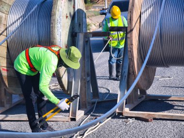 Yol boyunca yeni direklere yüksek gerilimli elektrik kabloları kurulumu.