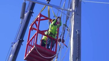  Asansördeki iki yetenekli işçi, uzun direğin elektrik bakımında güvenliği sağlıyorlar..