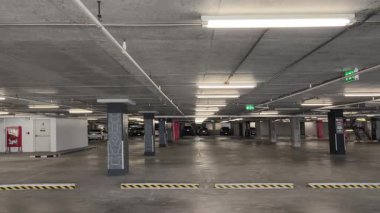 Geniş ve modern bir otopark. Temiz hatları ve bol ışıklandırması var. 