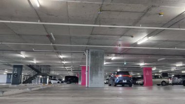 Modern bir elektrikli araç, çağdaş bir otoparkın içine park ediyor..