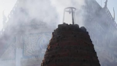 Eski Tayland tapınağındaki havai fişek fırınından çıkan duman kötü ruhları defetmek için dalgalanır..