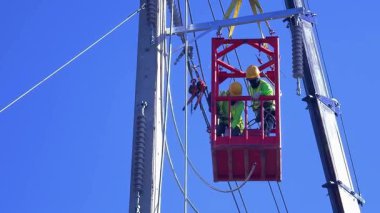  Asansördeki iki yetenekli işçi, uzun direğin elektrik bakımında güvenliği sağlıyorlar..