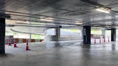 Bir araba, çeşitli koni ve tabelalarla işaretlenmiş park alanından dikkatle geçiyor..