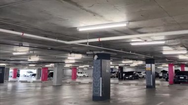 Geniş ve modern bir otopark. Temiz hatları ve bol ışıklandırması var. 