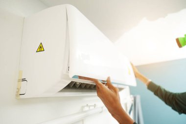 İşçi düzgün çalışması için klimayı temizler ve onarır..