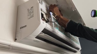 Bir teknisyen duvara monte edilmiş klimayı tamir eder ve havalandırma sistemini tamir eder.. 