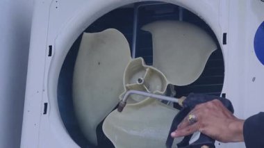 Bir teknisyen duvara monte edilmiş klimayı duruluyor ve havalandırma sistemini tamir ediyor..