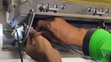 Bir teknisyen duvara monte edilmiş klimayı tamir eder ve havalandırma sistemini tamir eder.. 