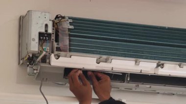 Bir teknisyen duvara monte edilmiş klimayı tamir eder ve havalandırma sistemini tamir eder.. 