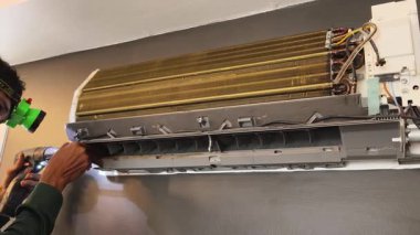 Bir teknisyen duvara monte edilmiş klimayı tamir eder ve havalandırma sistemini tamir eder.. 