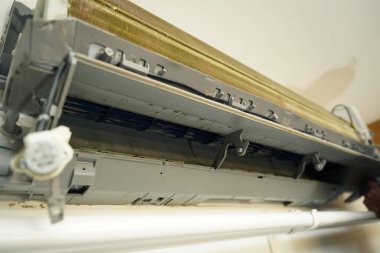 İşçi düzgün çalışması için klimayı temizler ve onarır..