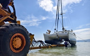 Sarı traktör güzel bir sahil bölgesinde sudan bir tekne çıkarıyor..