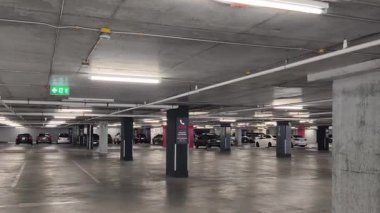 Geniş ve modern bir otopark. Temiz hatları ve bol ışıklandırması var. 