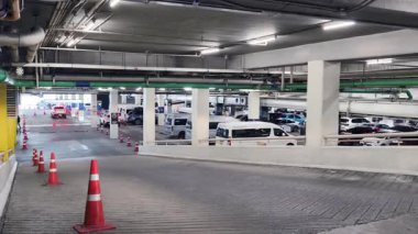 Bir araba, çeşitli koni ve tabelalarla işaretlenmiş park alanından dikkatle geçiyor..