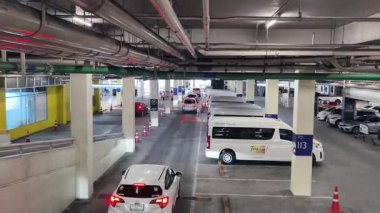 Bir araba, çeşitli koni ve tabelalarla işaretlenmiş park alanından dikkatle geçiyor..