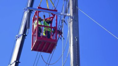  Asansördeki iki yetenekli işçi, uzun direğin elektrik bakımında güvenliği sağlıyorlar..