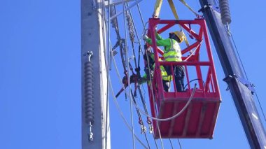  Asansördeki iki yetenekli işçi, uzun direğin elektrik bakımında güvenliği sağlıyorlar..