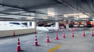 Bir araba, çeşitli koni ve tabelalarla işaretlenmiş park alanından dikkatle geçiyor..