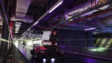 Bir grup kapalı pistte gokart yarıştırıyor motor seslerinin ve keskin virajların tadını çıkarıyor.