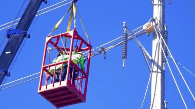  Asansördeki iki yetenekli işçi, uzun direğin elektrik bakımında güvenliği sağlıyorlar..