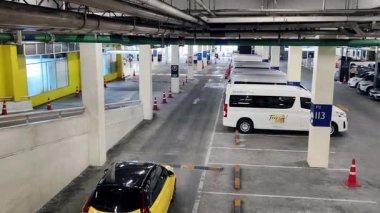 Bir araba, çeşitli koni ve tabelalarla işaretlenmiş park alanından dikkatle geçiyor..