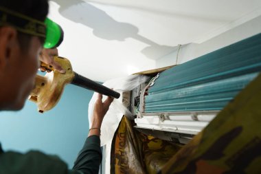 İşçi düzgün çalışması için klimayı temizler ve onarır..