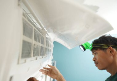 İşçi düzgün çalışması için klimayı temizler ve onarır..