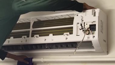 Bir teknisyen duvara monte edilmiş klimayı tamir eder ve havalandırma sistemini tamir eder.. 