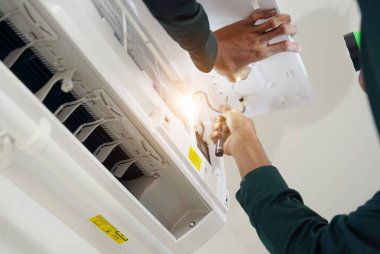 İşçi düzgün çalışması için klimayı temizler ve onarır..