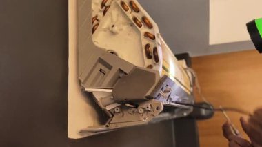 Bir teknisyen duvara monte edilmiş klimayı tamir eder ve havalandırma sistemini tamir eder.. 