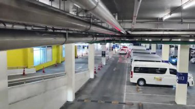 Bir araba, çeşitli koni ve tabelalarla işaretlenmiş park alanından dikkatle geçiyor..
