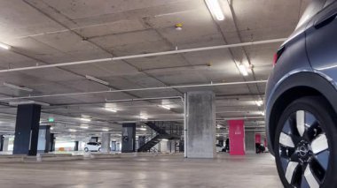 Modern bir elektrikli araç, çağdaş bir otoparkın içine park ediyor..