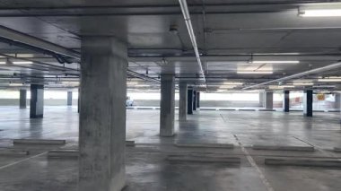 Geniş ve modern bir otopark. Temiz hatları ve bol ışıklandırması var. 