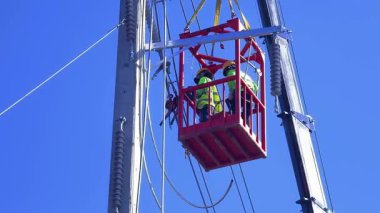  Asansördeki iki yetenekli işçi, uzun direğin elektrik bakımında güvenliği sağlıyorlar..