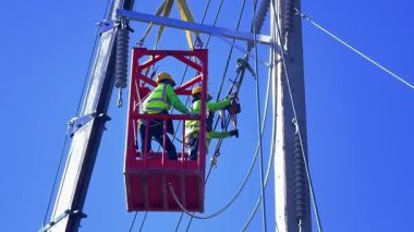  Asansördeki iki yetenekli işçi, uzun direğin elektrik bakımında güvenliği sağlıyorlar..