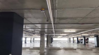 Geniş ve modern bir otopark. Temiz hatları ve bol ışıklandırması var. 