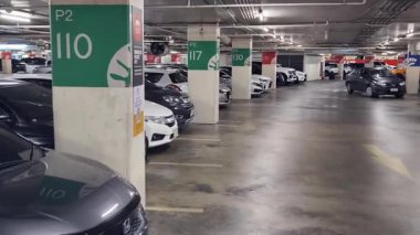 Düzenli olarak dizilmiş çeşitli arabaların sergilendiği modern bir otopark.