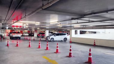 Bir araba, çeşitli koni ve tabelalarla işaretlenmiş park alanından dikkatle geçiyor..