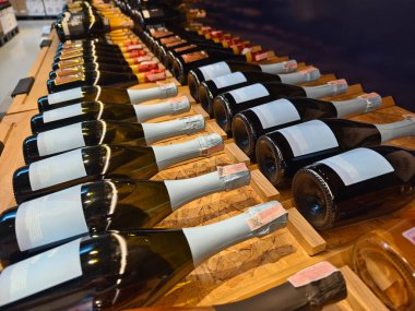 Şampanyaların çeşitleri zarif bir şekilde ahşap bir rafta dizilmiştir..