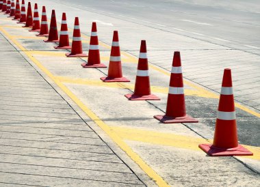 Bir sıra kırmızı ve beyaz trafik konisi bir yol tarafından yerleştirilir..