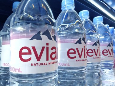 FUKET, THAILAND - 8 Mart 2025: Evian maden suyu şişeleri düzgünce bir rafa dizilmiştir.