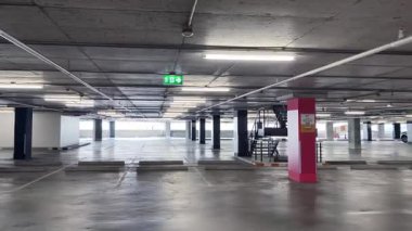 Geniş ve modern bir otopark. Temiz hatları ve bol ışıklandırması var. 