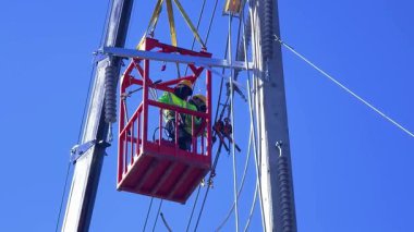  Asansördeki iki yetenekli işçi, uzun direğin elektrik bakımında güvenliği sağlıyorlar..